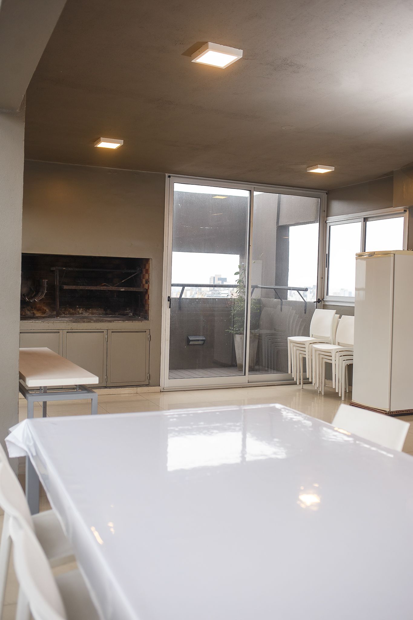Indoor dining space with large table, grill, and access to a balcony with city views.