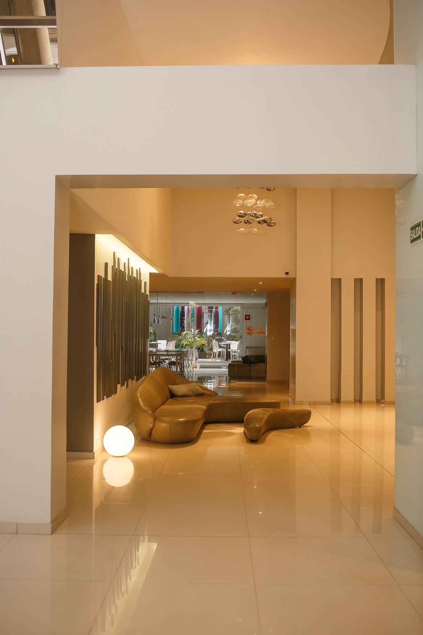 Modern interior with a beige sectional sofa, polished floors, and decorative lighting.