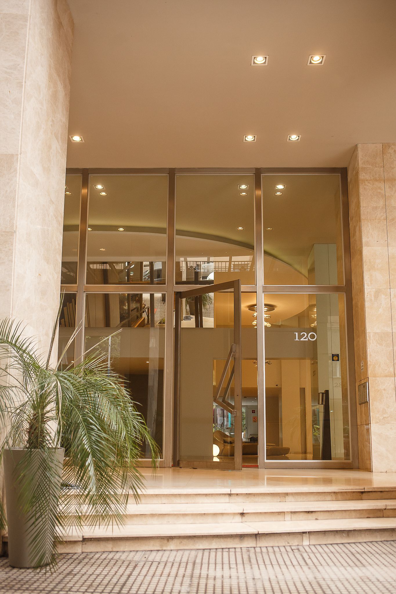 Entrance to a building with glass doors, stone facade, and steps. A potted plant sits to the left.
