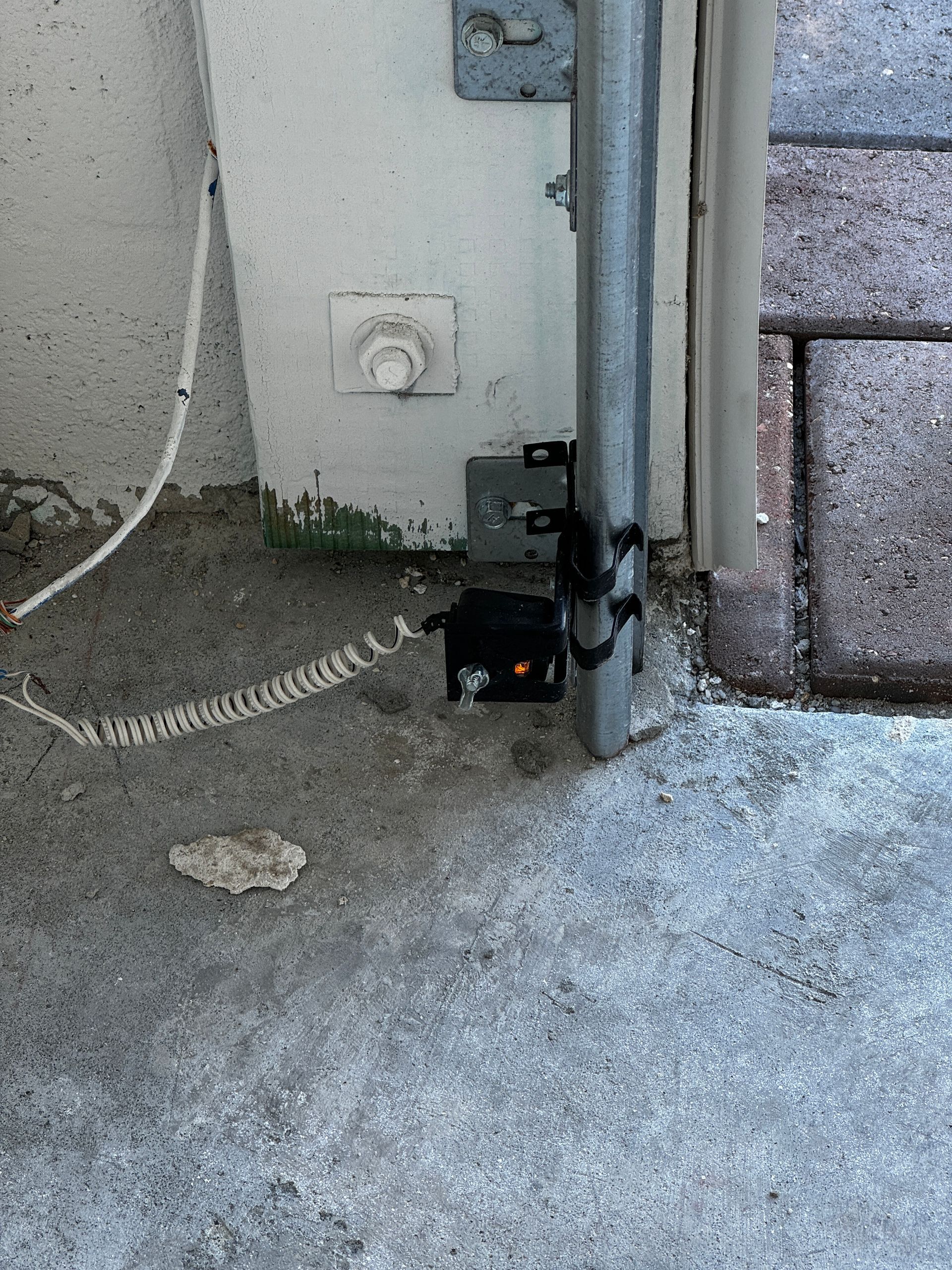 A telephone is sitting on the ground next to a metal pole.