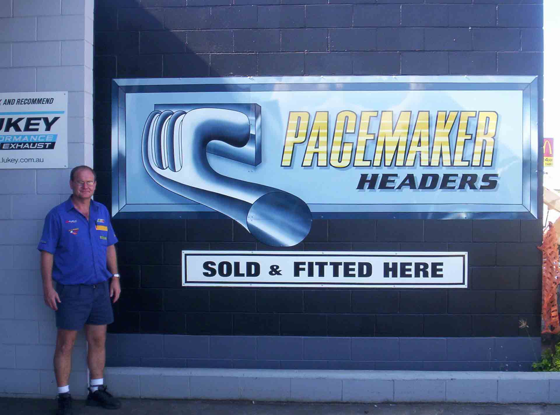 Bob next to Pacemaker Header Sign — Bob Parkes Automotive In Hyde Park, QLD
