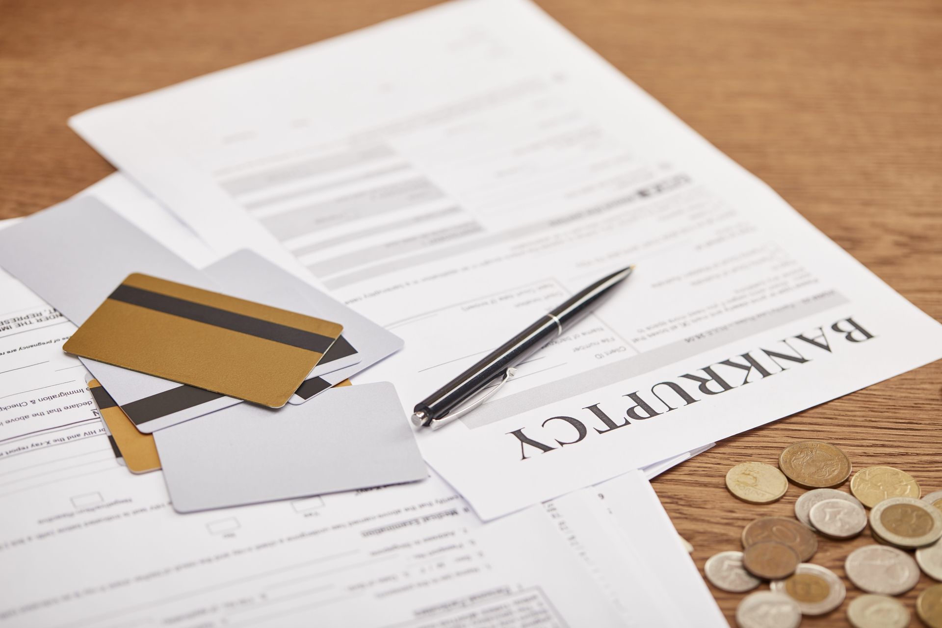 Financial paperwork with cards, pen, and coins on a desk