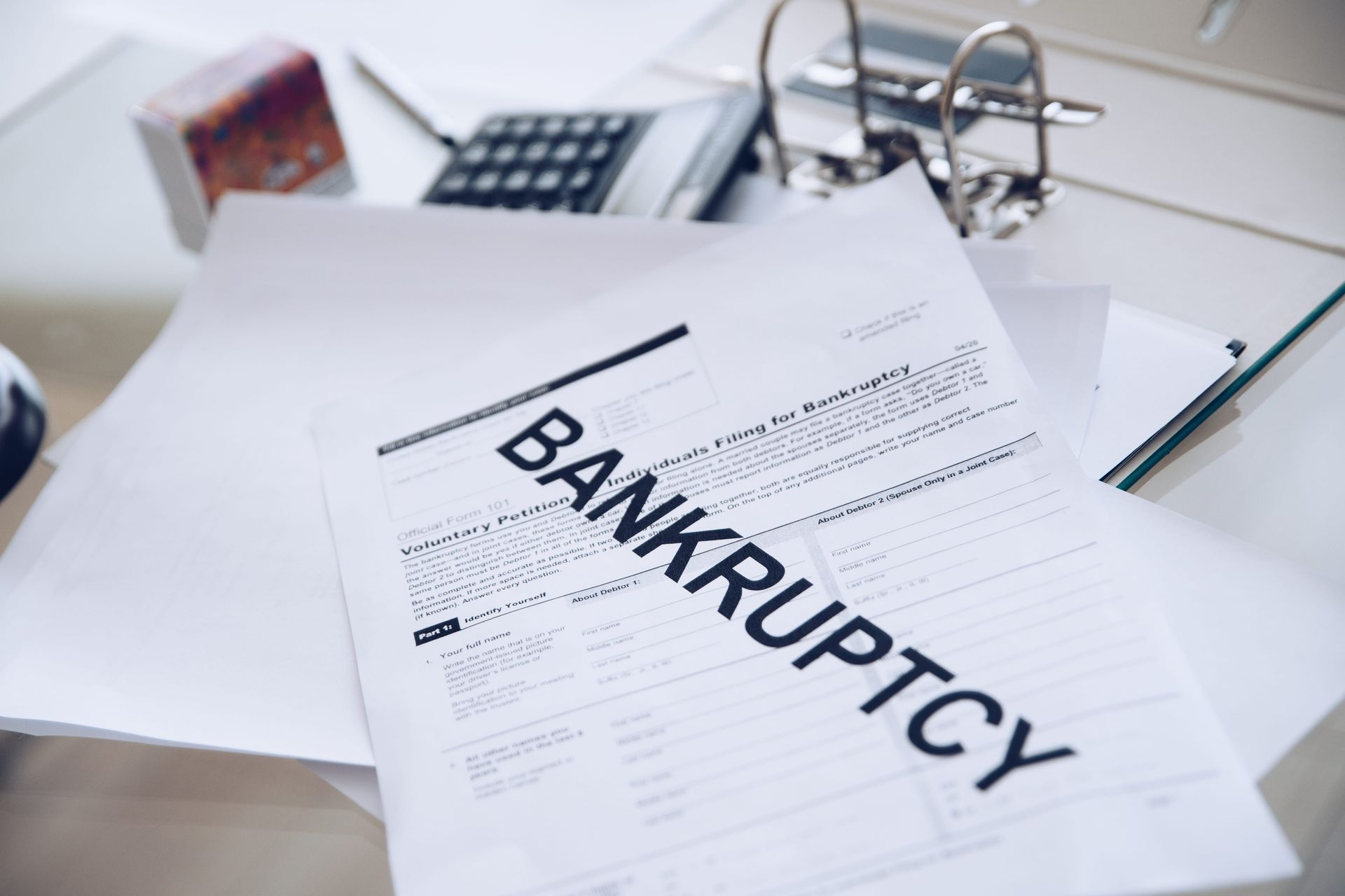 Bankruptcy documents on a desk with a binder and calculator