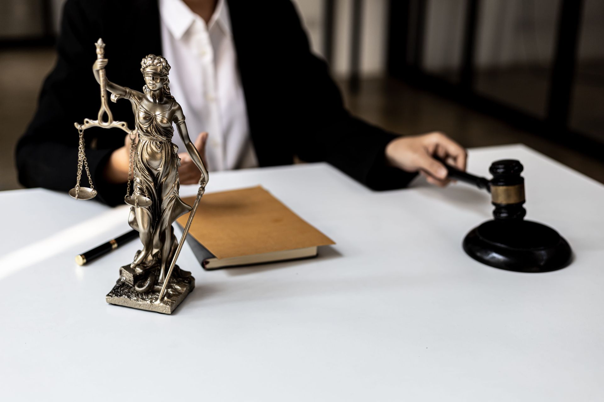 Lawyer’s desk with justice statue, gavel, and folder in a courtroom setting