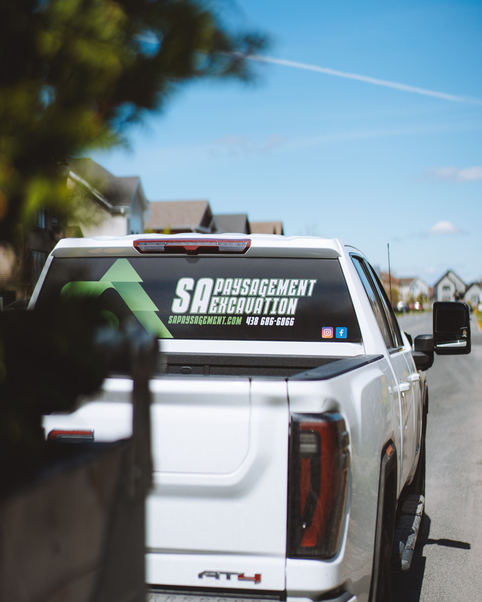 Camion blanc avec un autocollant « SA » garé dans une rue, un ciel bleu vif en arrière-plan.
