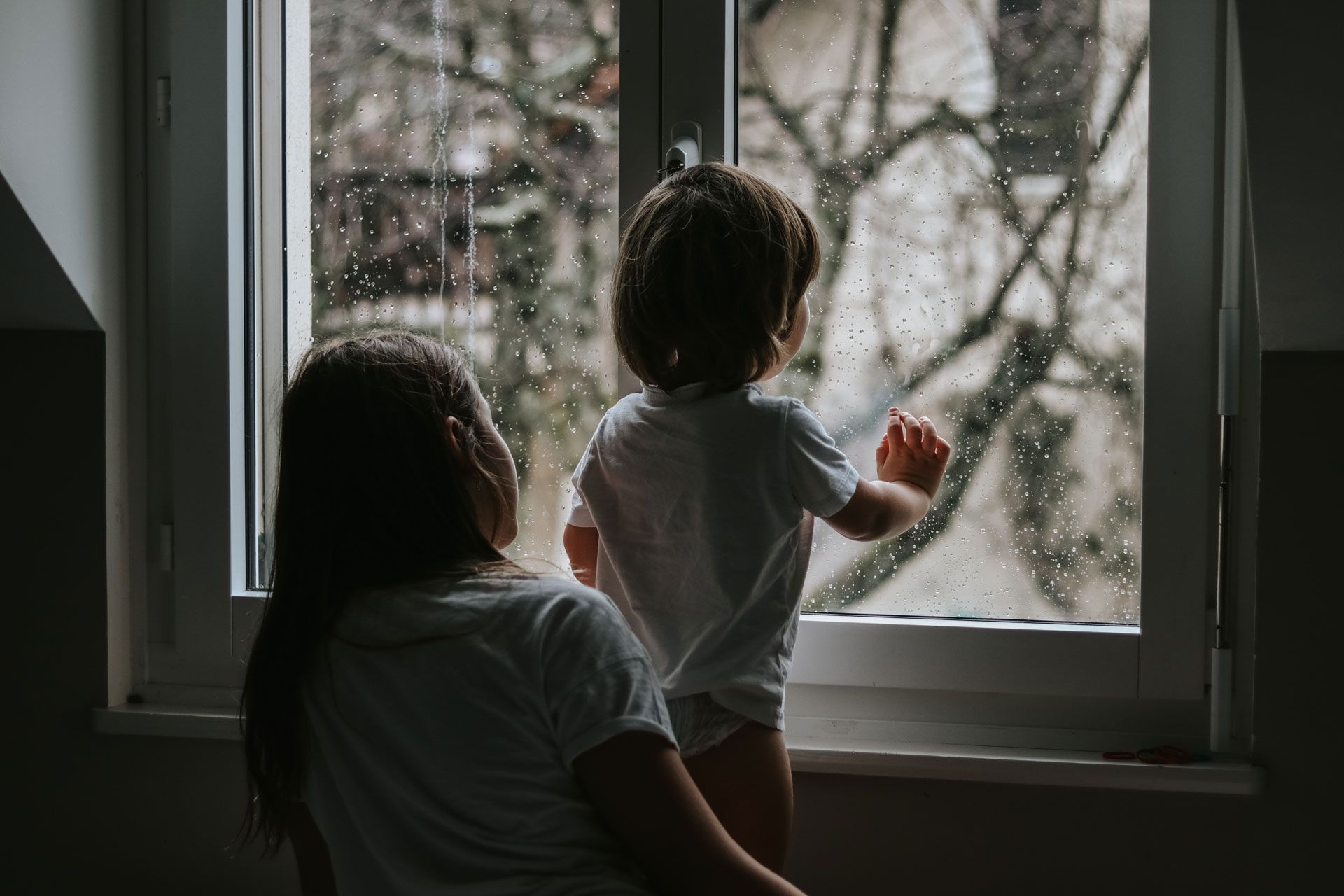 A woman and a child are looking out of a window.