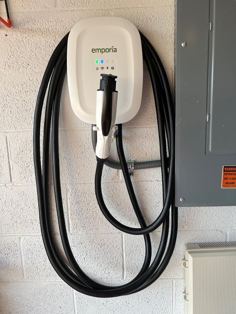 a white electric car charger is hanging on a wall