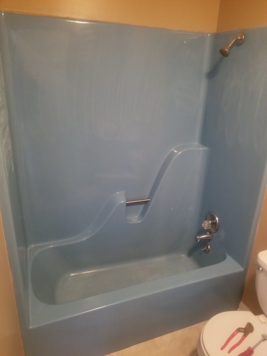a blue bathtub in a bathroom next to a toilet