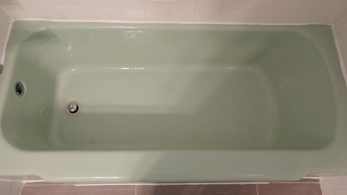 a green bathtub in a bathroom with a drain .