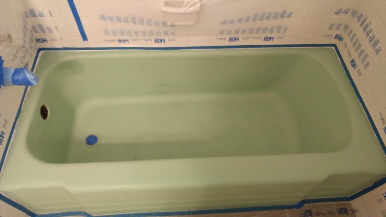 a bathtub is being painted green in a bathroom .