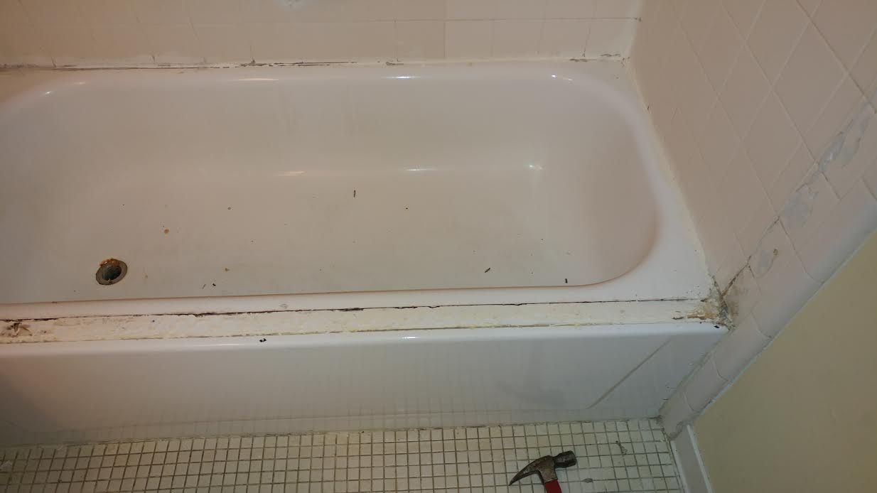 a bathtub with a hammer on the floor next to it .