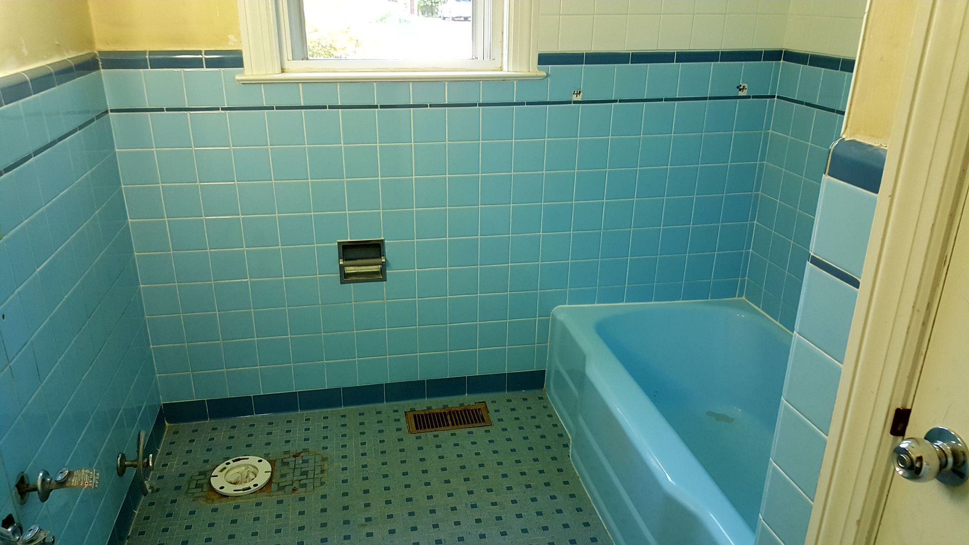 a bathroom with blue tiles and a blue tub .