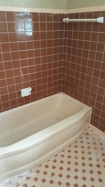a bathroom with brown tile walls and a white bathtub .