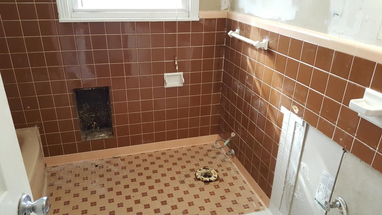 a bathroom with brown tiles and a window .
