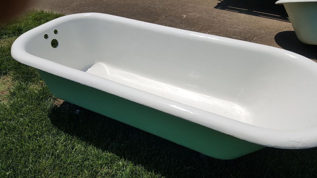 a white bathtub is sitting on top of a lush green field .