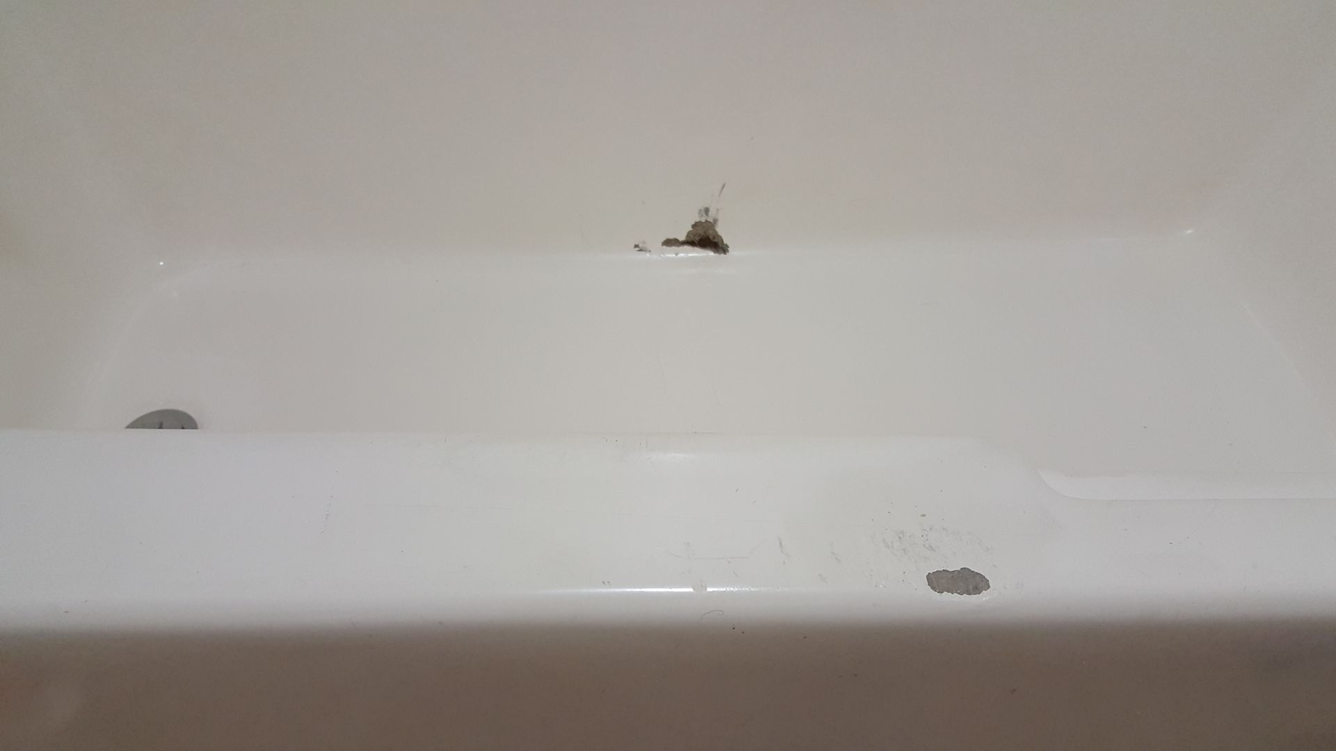 a white bathtub with a hole in the wall .
