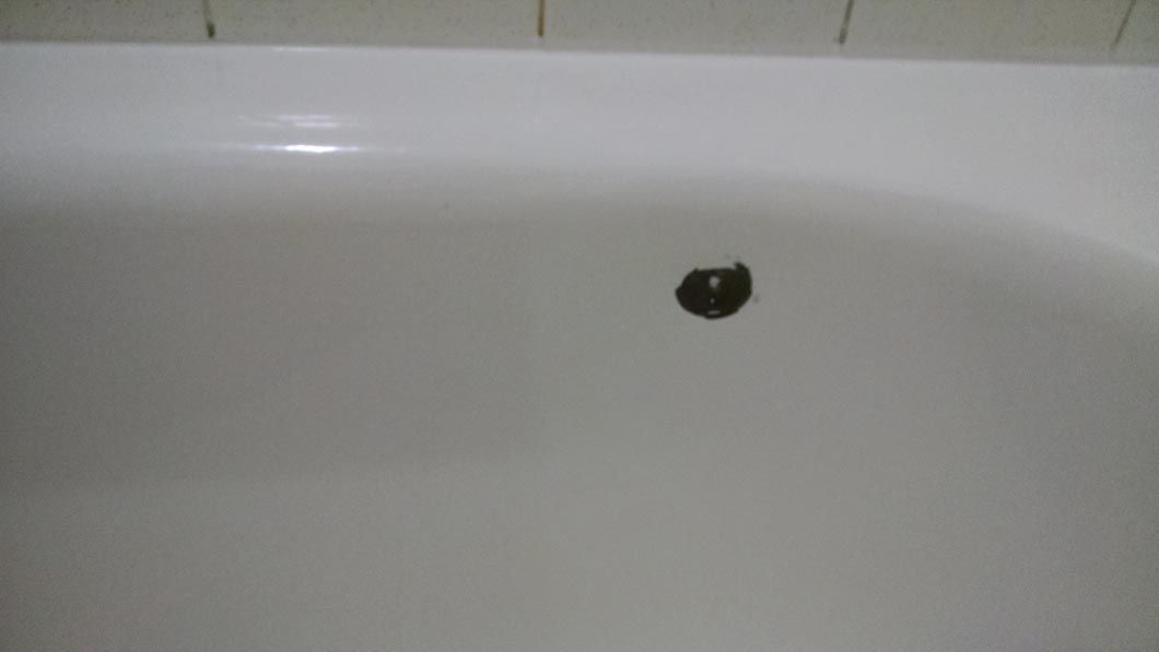 a white bathtub with a black hole in the drain .