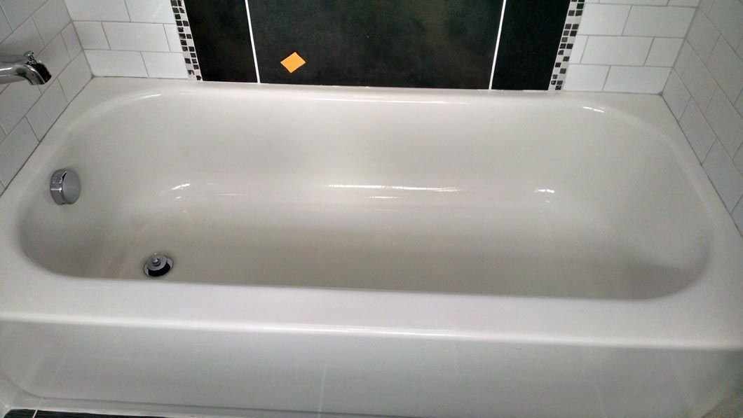 a white bathtub is sitting in a bathroom next to a black and white tile wall .