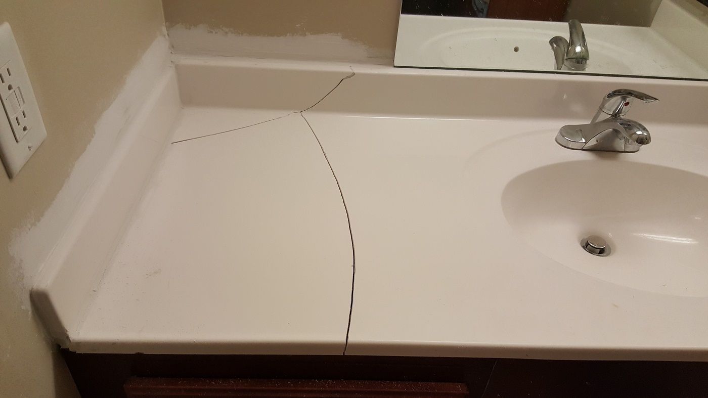 a bathroom sink with a cracked counter top