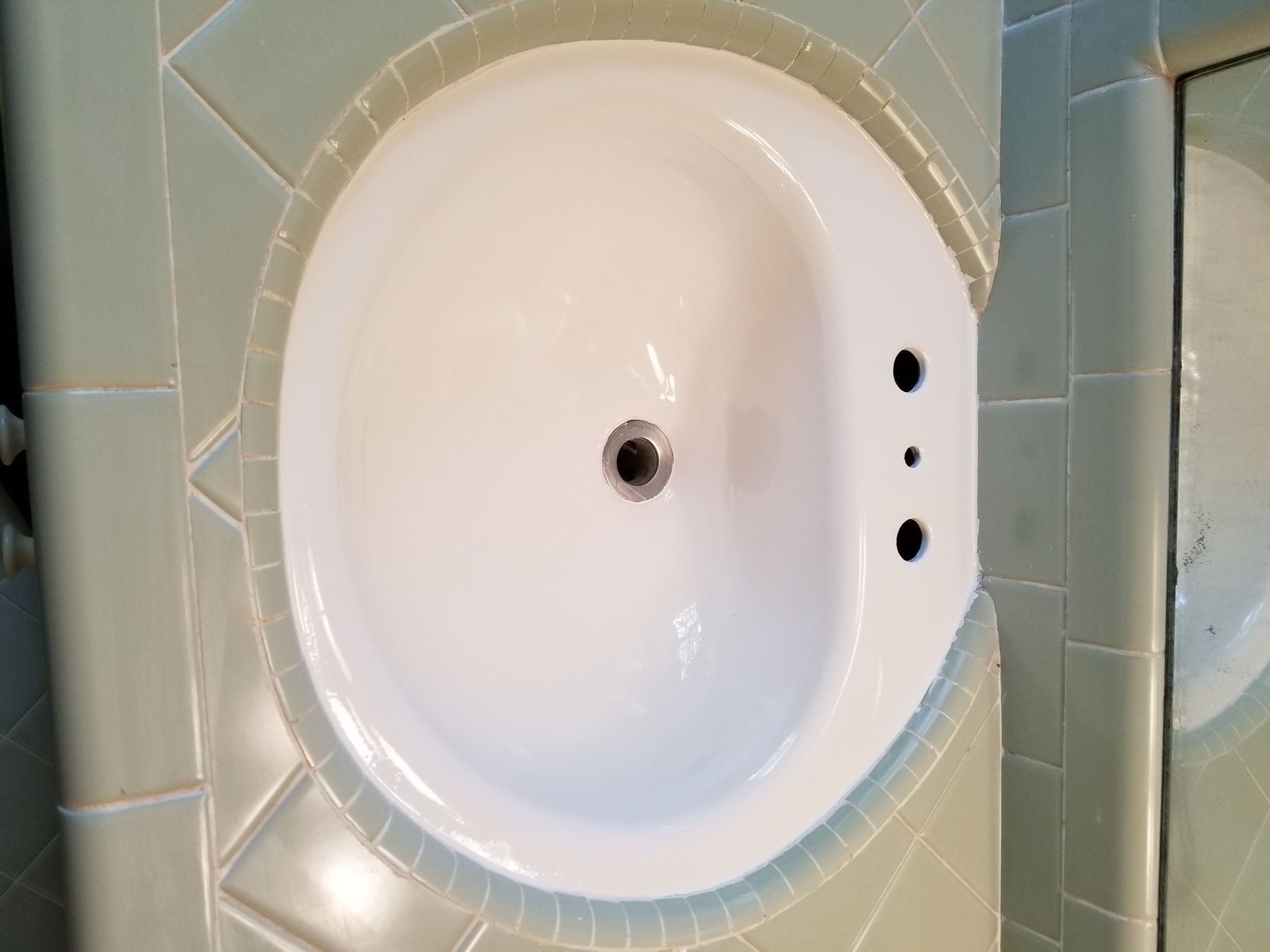 a white sink is sitting on a tiled counter in a bathroom.