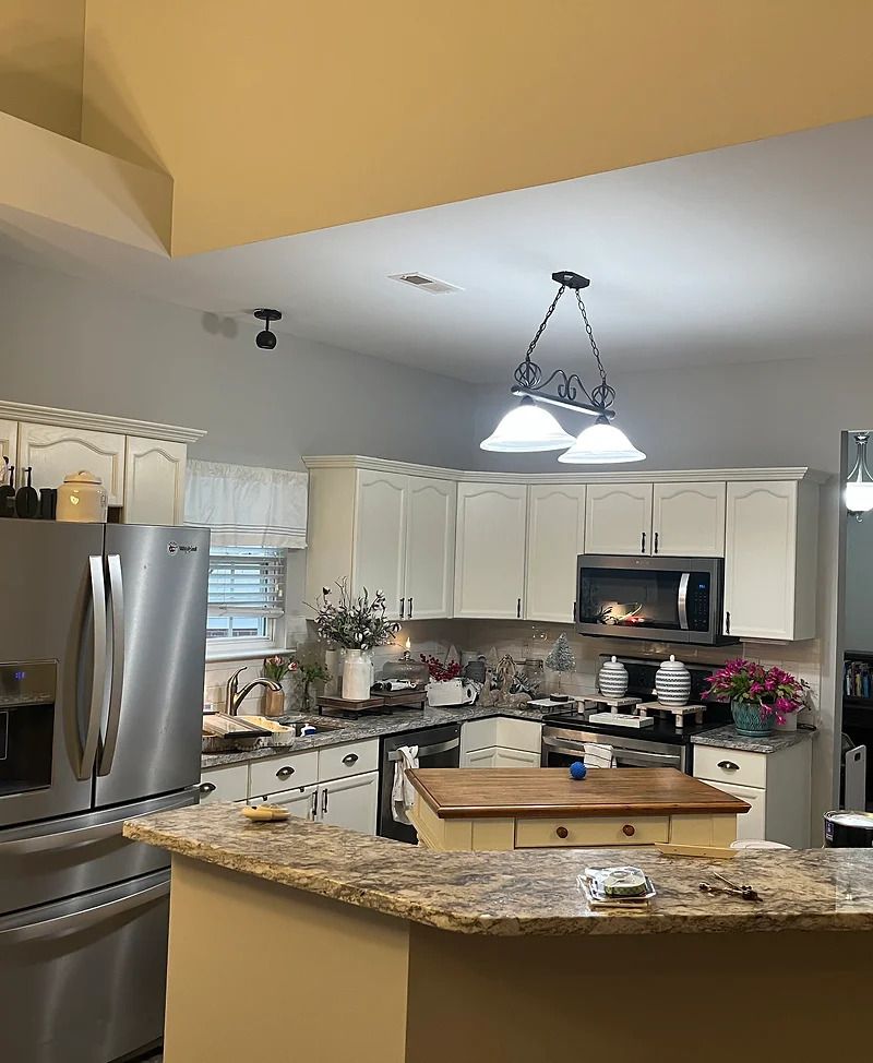 Kitchen with white cabinets, stainless steel appliances, island, and pendant lights.
