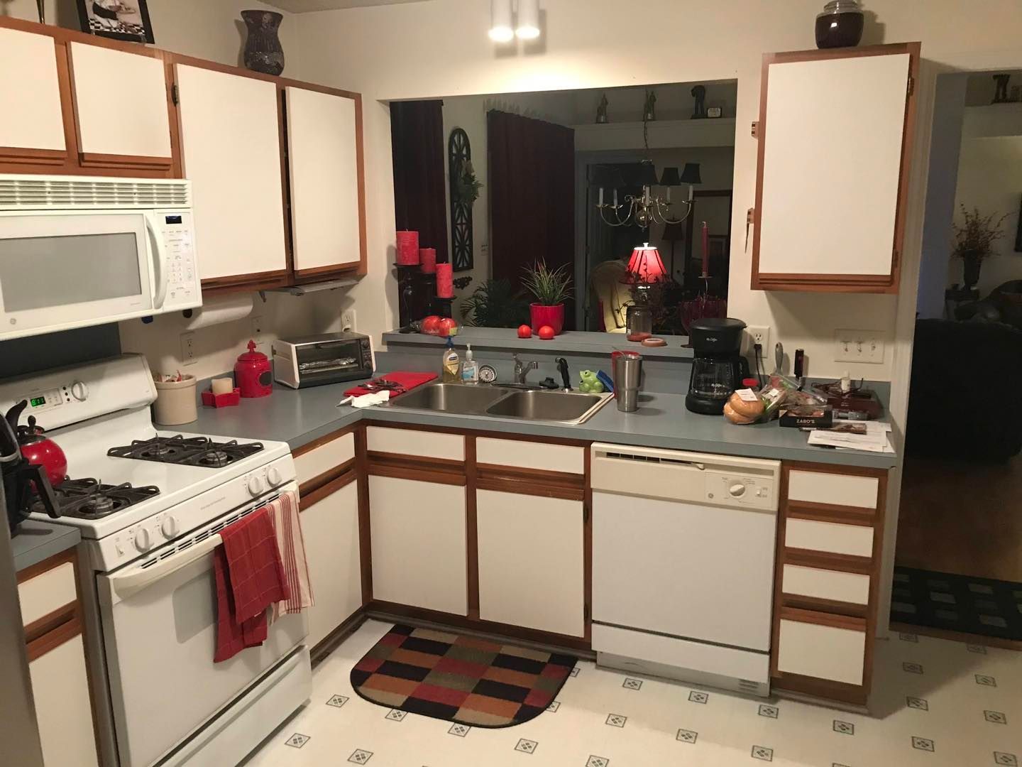 Modern U-shaped kitchen with white cabinets, gold trim, and a black window.