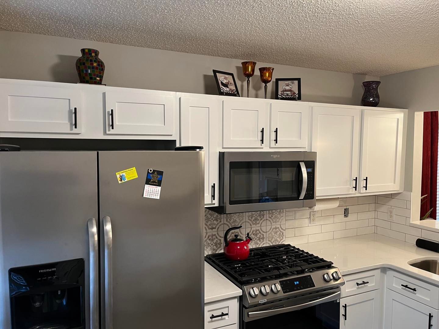 White kitchen cabinets with gold trim, blue tile backsplash, and range hood.