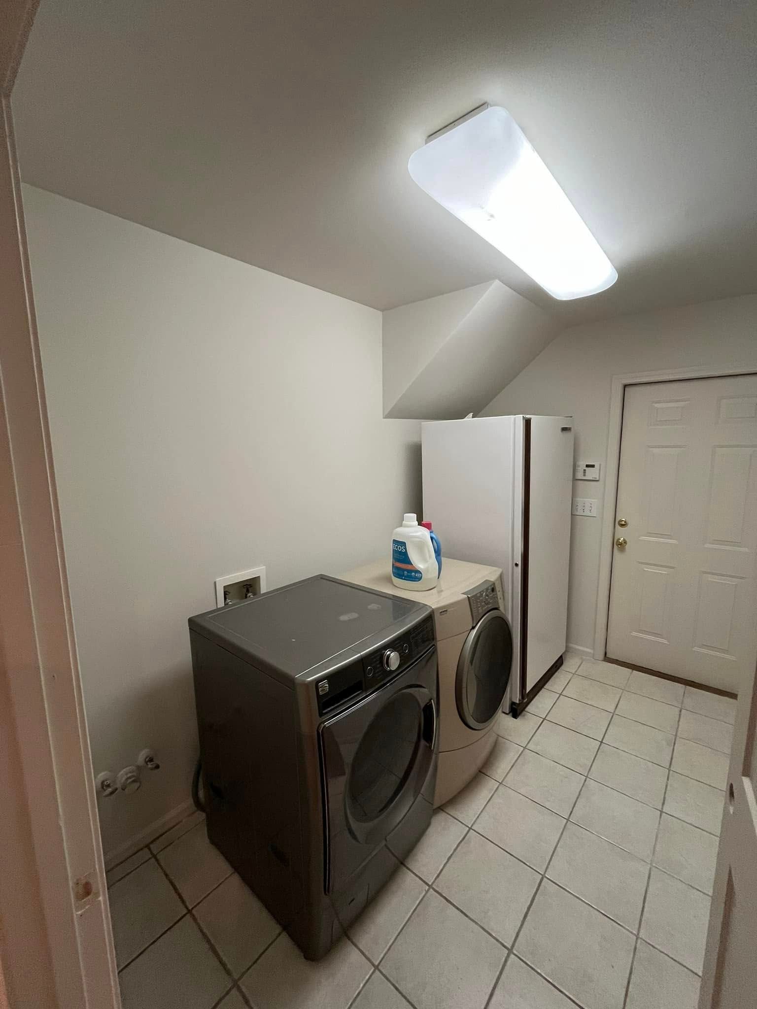 Mall interior with a blank white advertisement screen. Shiny floors reflect the stores and lights.