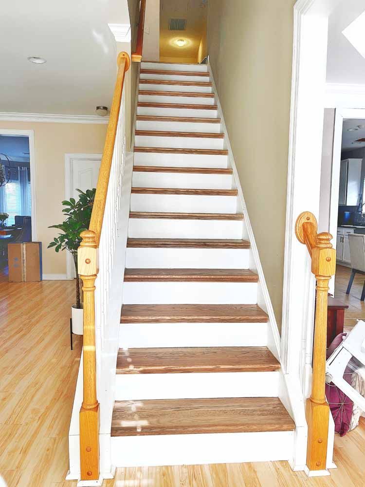 Wooden staircase with white risers and brown treads, wooden handrail, leading upward.