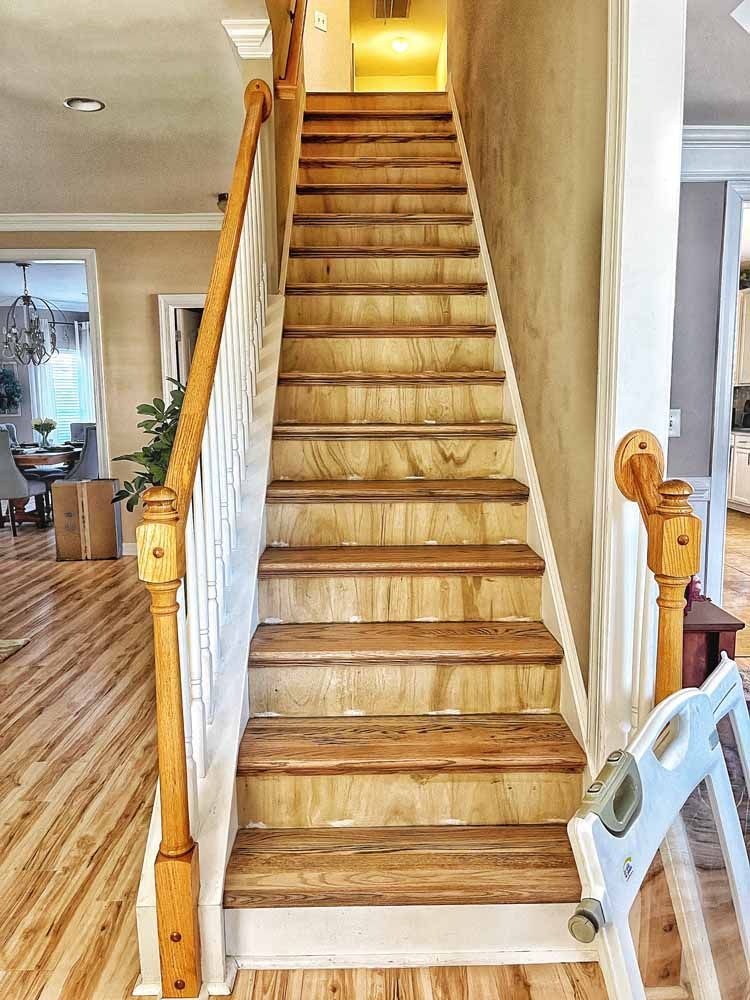 Wooden staircase with white banisters and a baby gate.