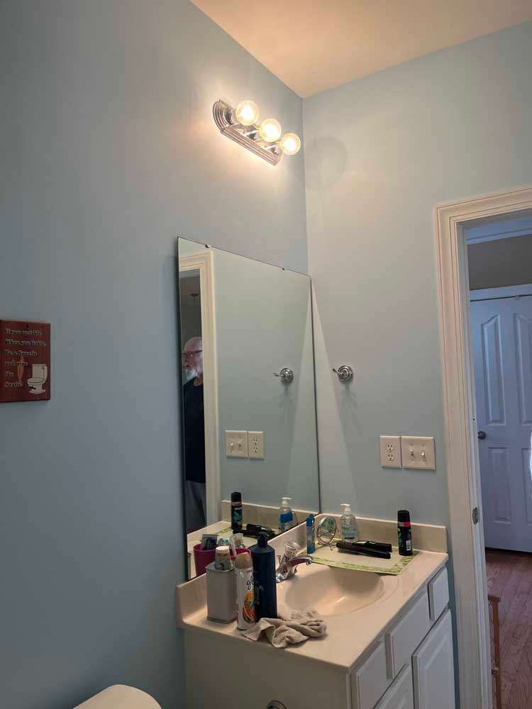 Bathroom with a vanity, mirror, and light fixture; light blue walls.
