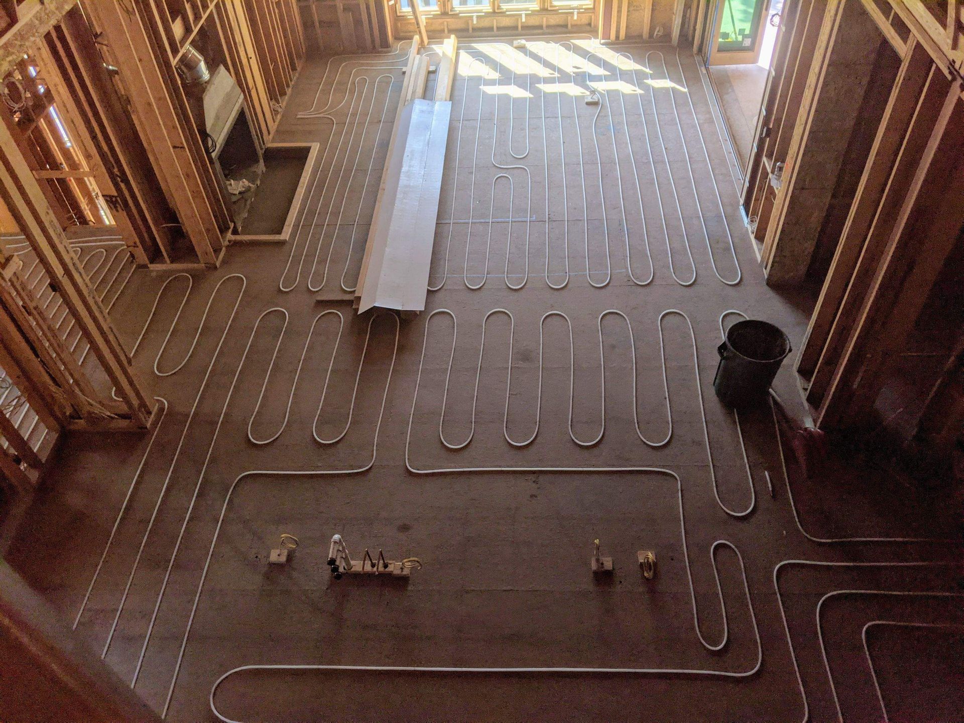 Radiant floor heating installation. Flexible tubing laid across subfloor in a new construction home.