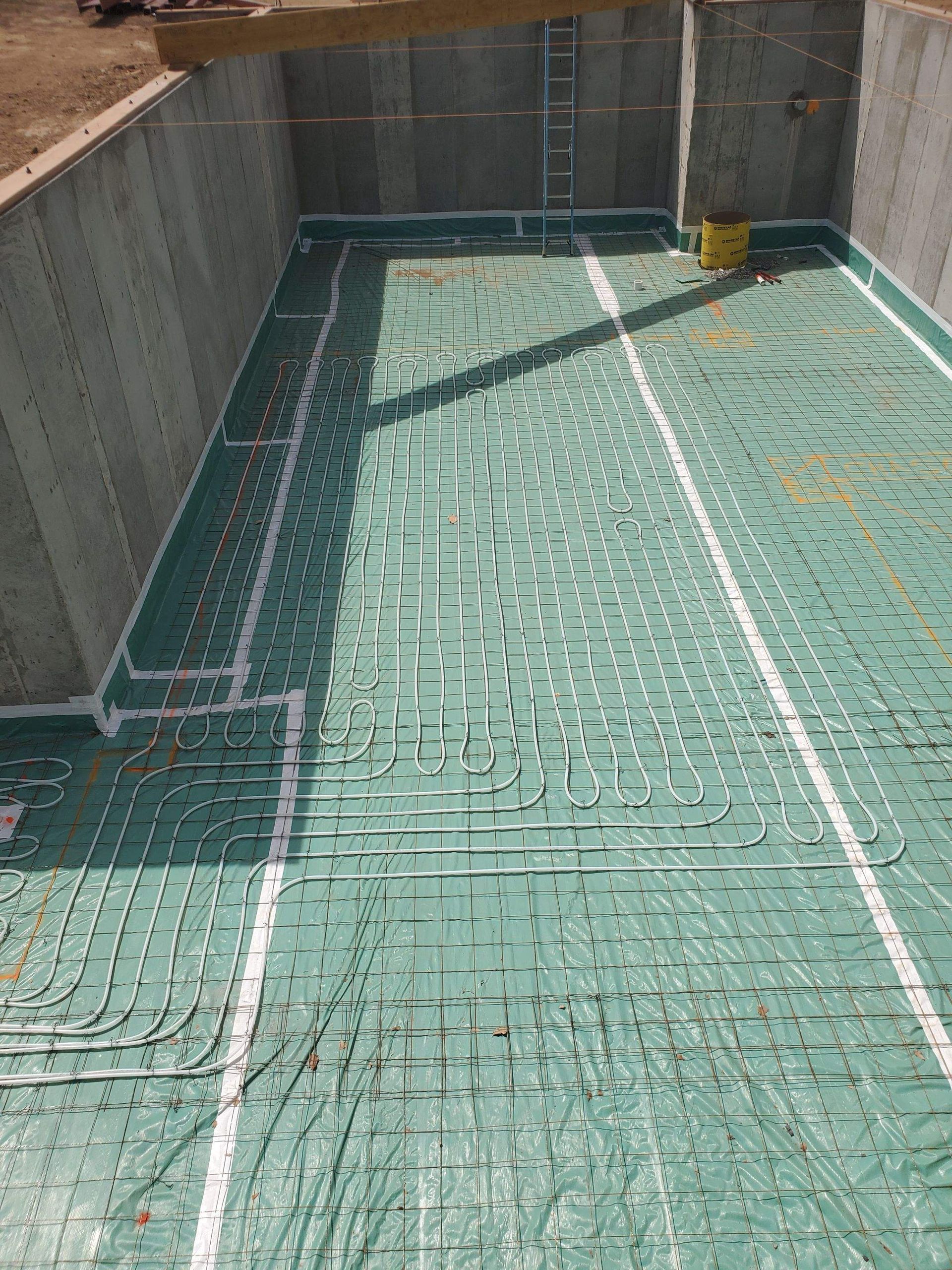 Green radiant floor system installed in a concrete basement; pipes are secured to insulation.