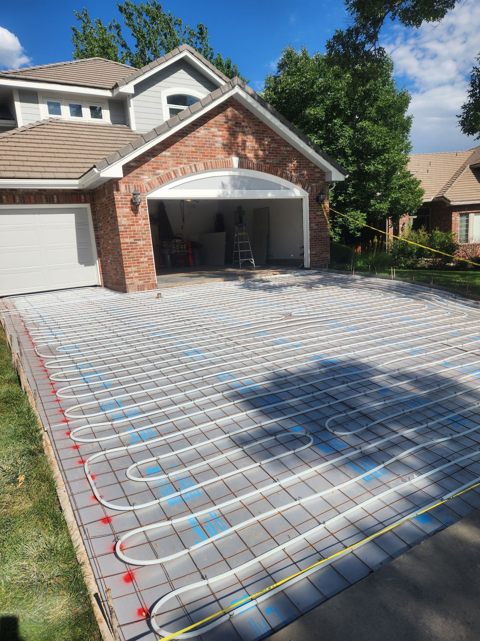 Driveway under construction; blue insulation, red wires, and a house in the background.