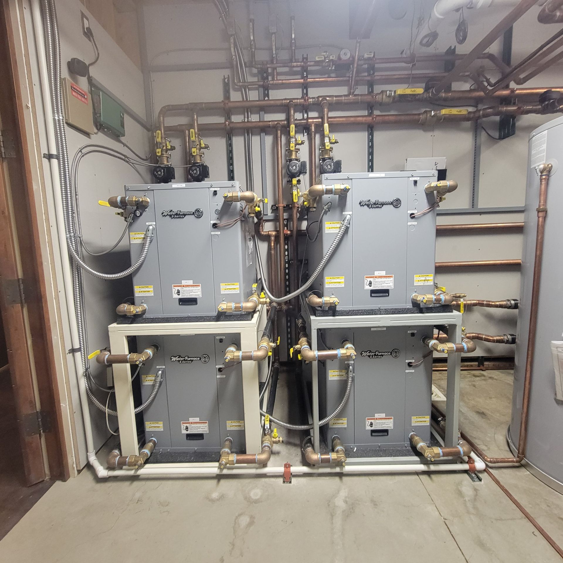 Water heater and plumbing in a basement with wooden framing, pipes, and a storage tank.