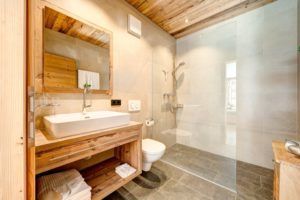 Ein Badezimmer mit Waschbecken, Toilette, Spiegel und ebenerdiger Dusche.