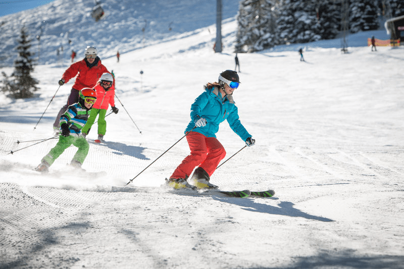 Eine Gruppe von Leuten fährt einen schneebedeckten Hang hinunter.
