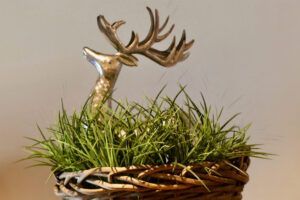 Eine Hirschstatue sitzt in einem Korb mit Gras.
