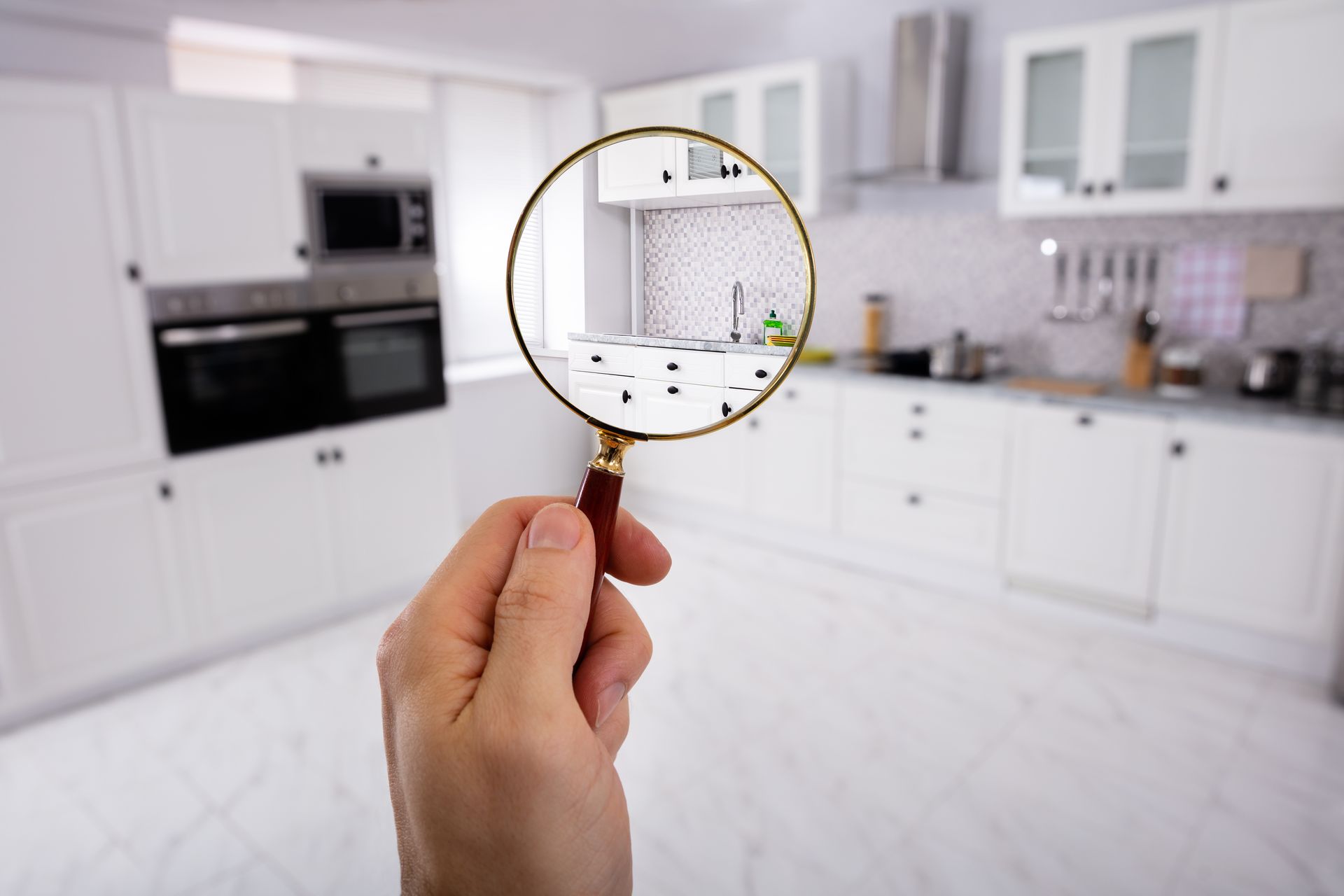 A person is holding a magnifying glass in front of a kitchen.
