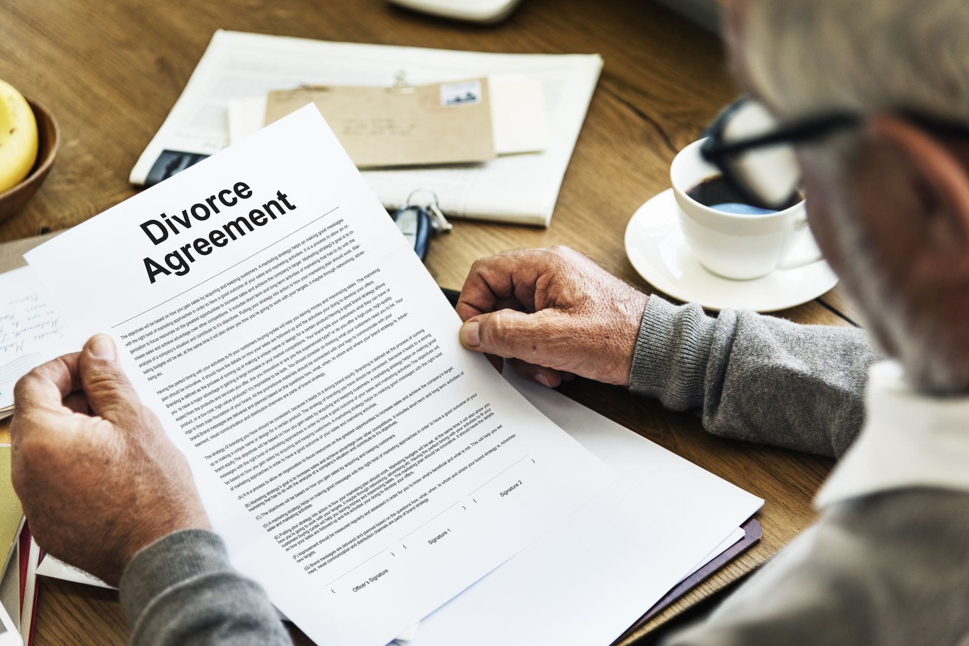 A man is sitting at a table reading a divorce agreement.