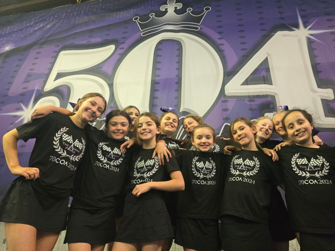 A group of young girls are posing for a picture in front of a sign that says 504