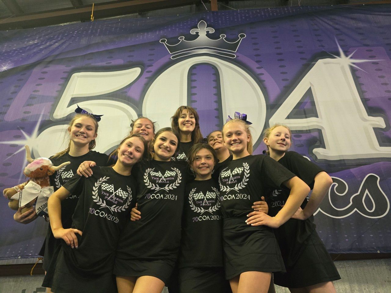 A group of girls are posing for a picture in front of a sign that says 504