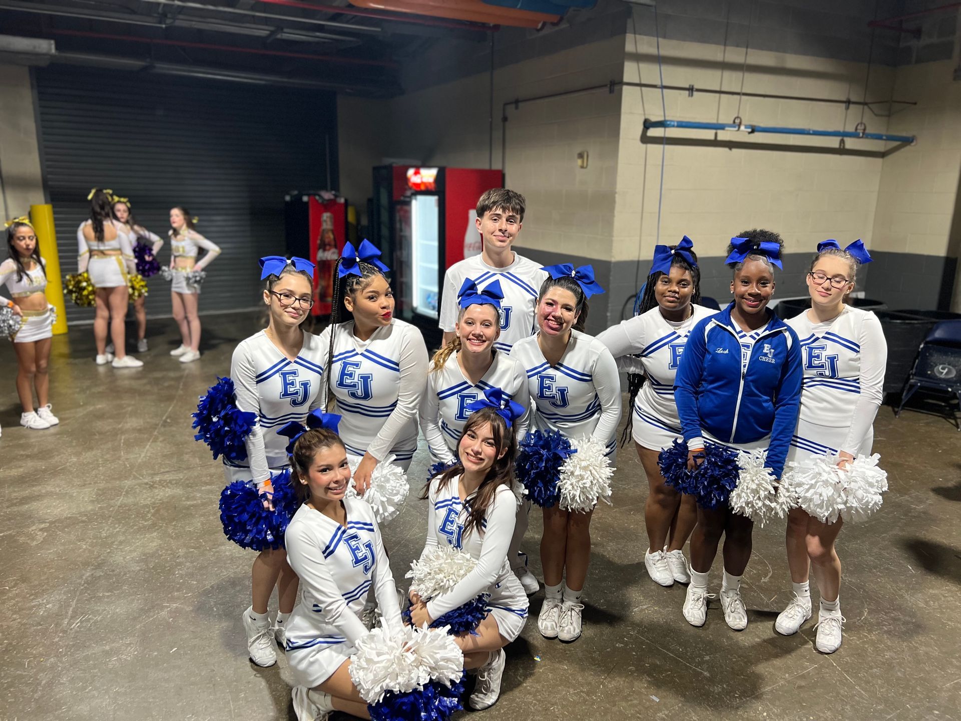 A group of cheerleaders are posing for a picture in a room.