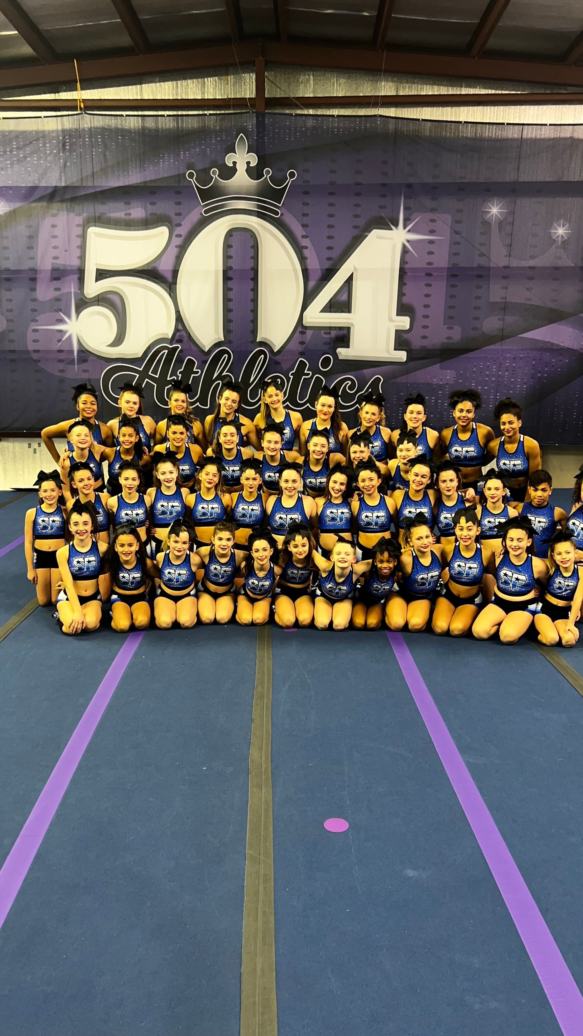 A group of cheerleaders are posing for a picture in a gym.