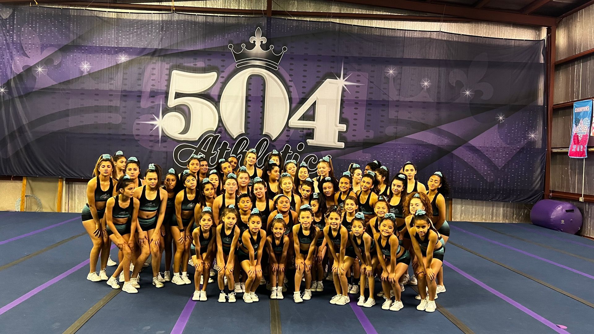 A group of cheerleaders are posing for a picture in front of a banner that says 504.