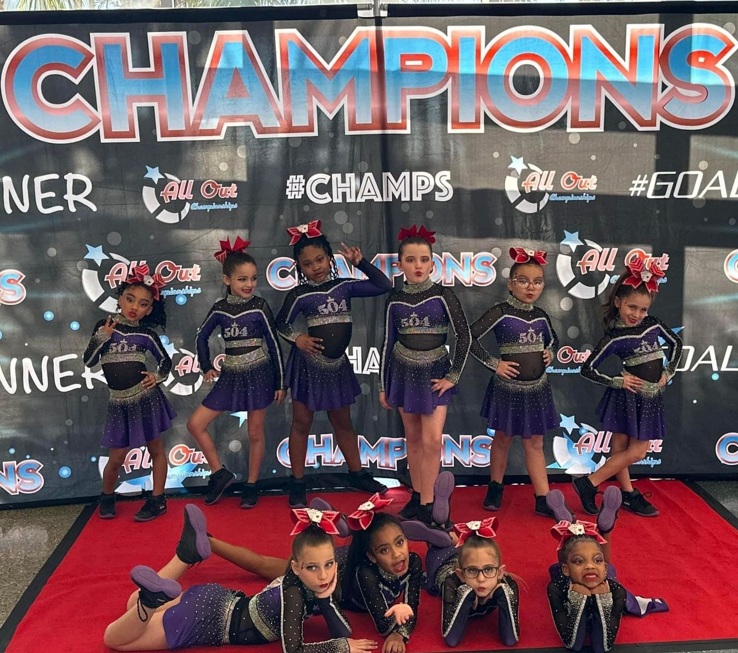 A group of cheerleaders are posing for a picture in front of a banner that says champions