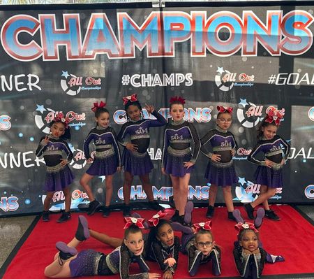 A group of cheerleaders are posing for a picture in front of a banner that says champions