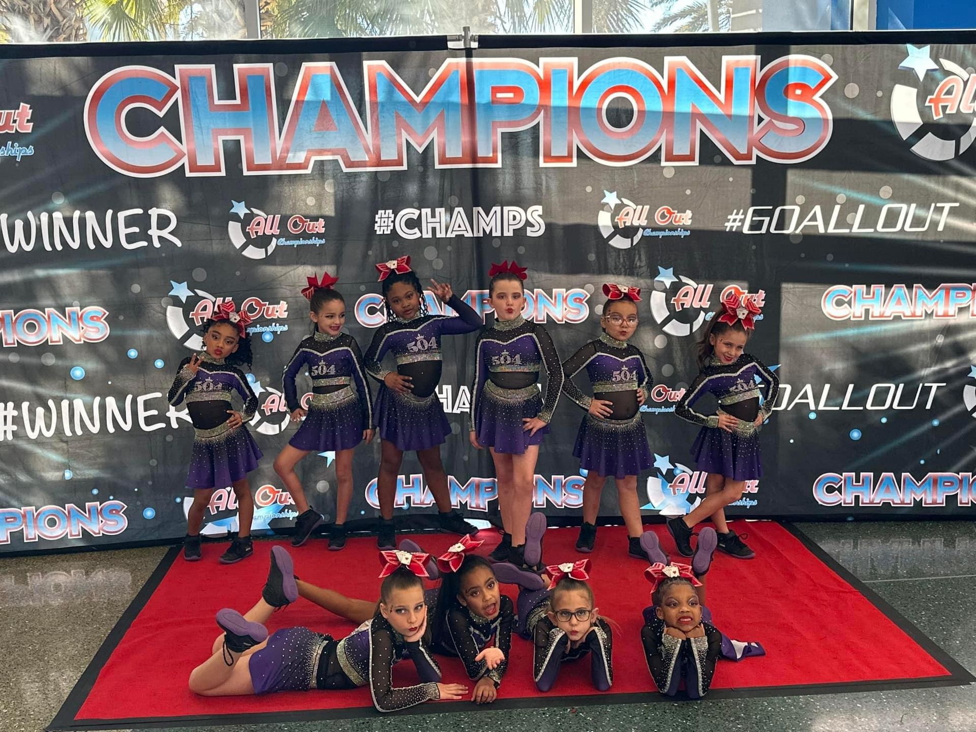 A group of cheerleaders pose in front of a banner that says champions