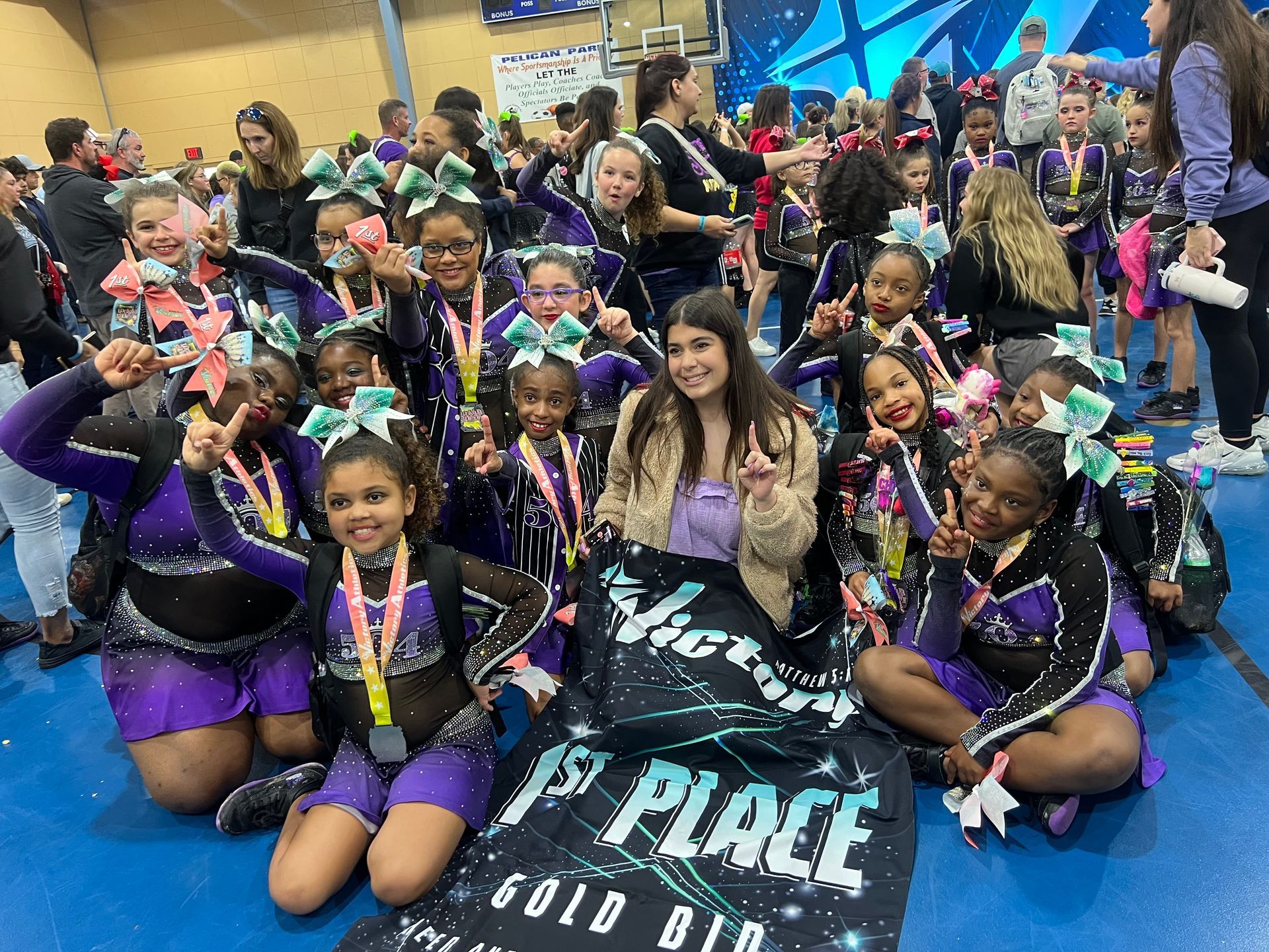 A group of cheerleaders are posing for a picture while sitting on the floor.