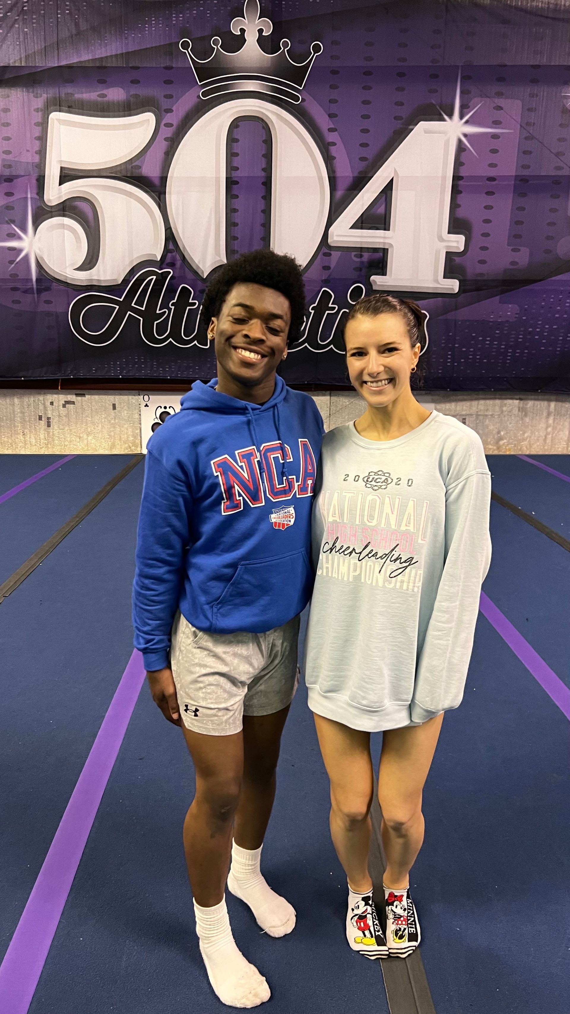 A man and a woman are standing next to each other on a purple track.